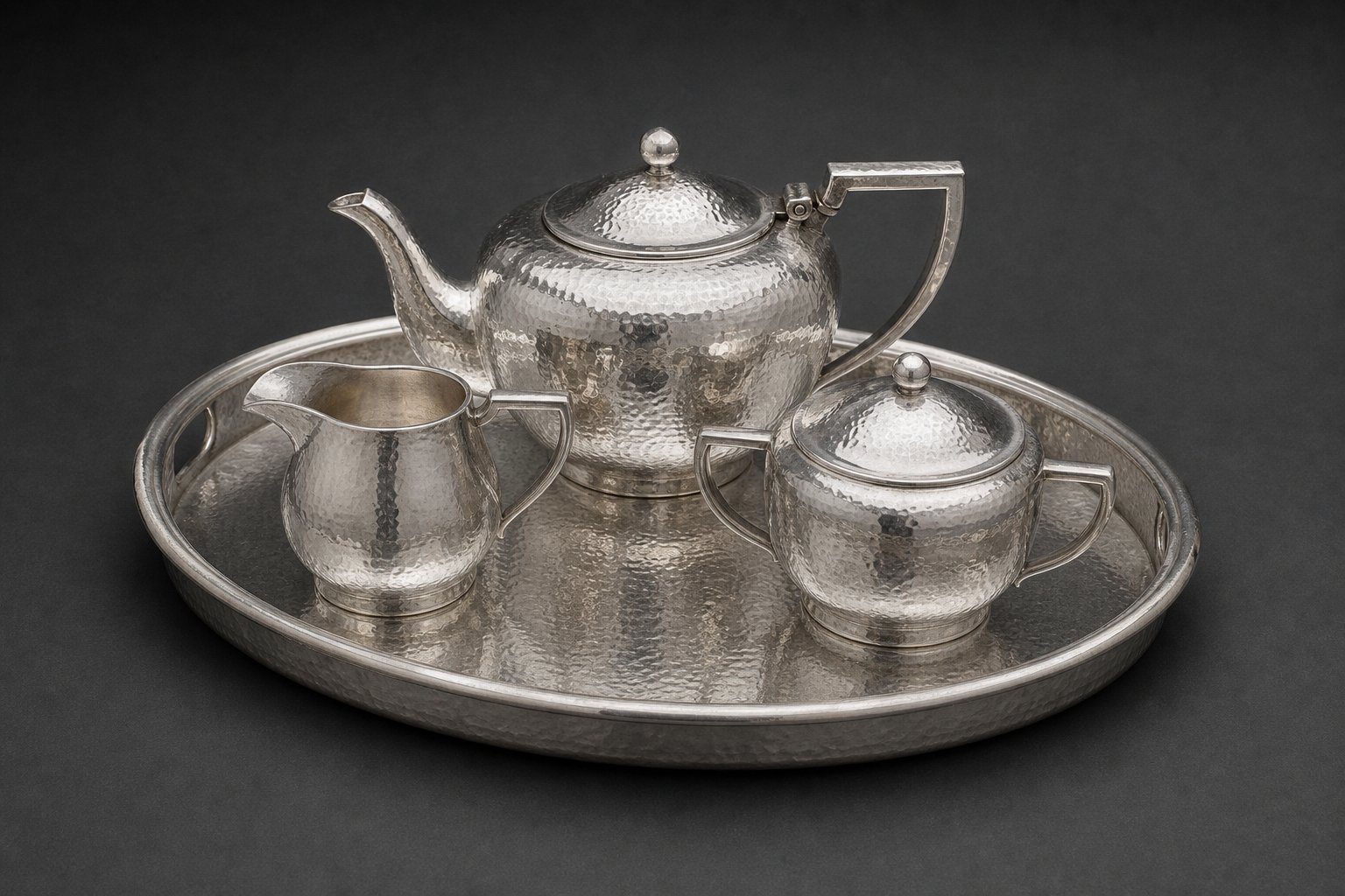 Hand-hammered silver tea service on charcoal seamless — auction catalog study