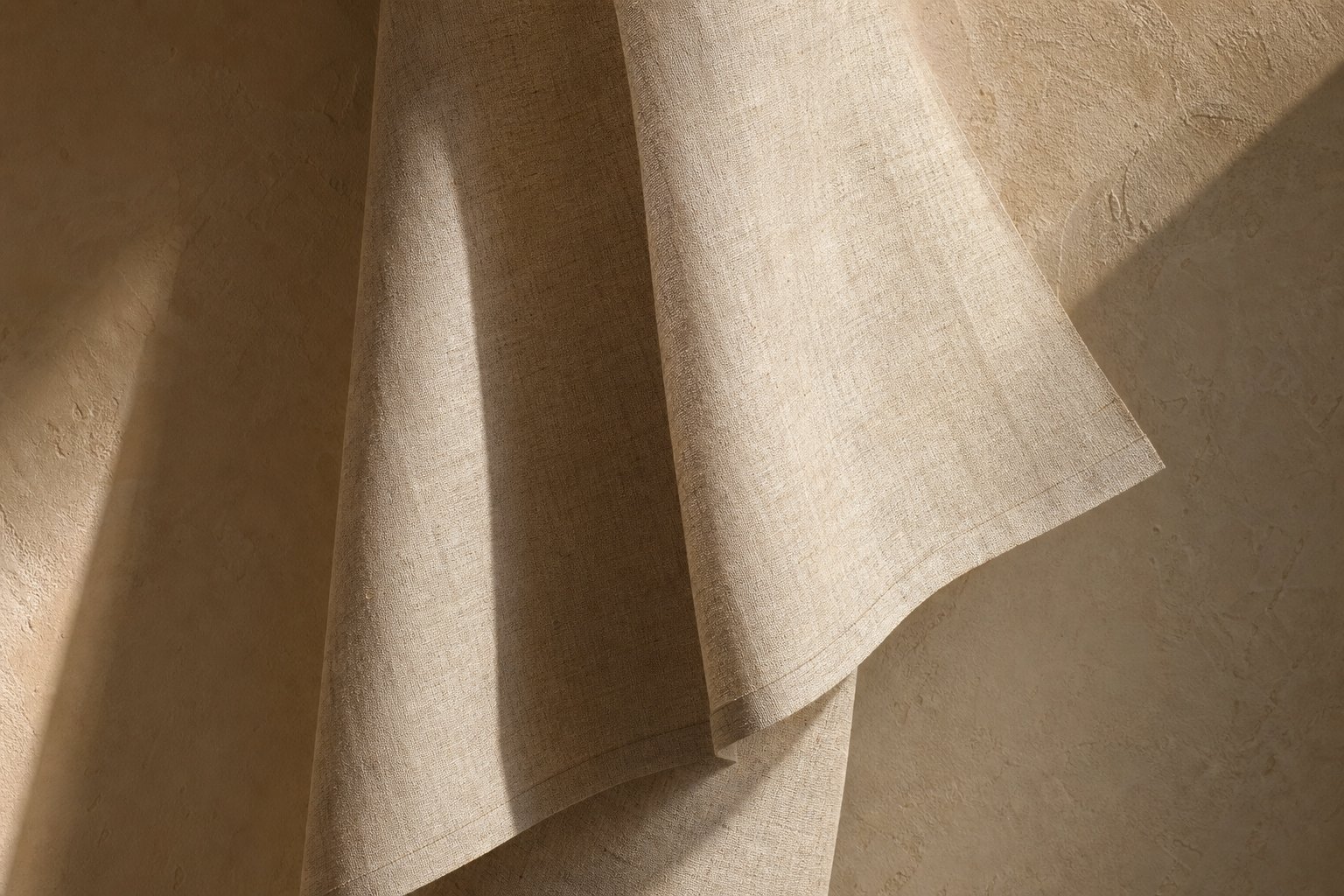 Unbleached linen falling in one broad sculptural fold against warm plaster — textile study