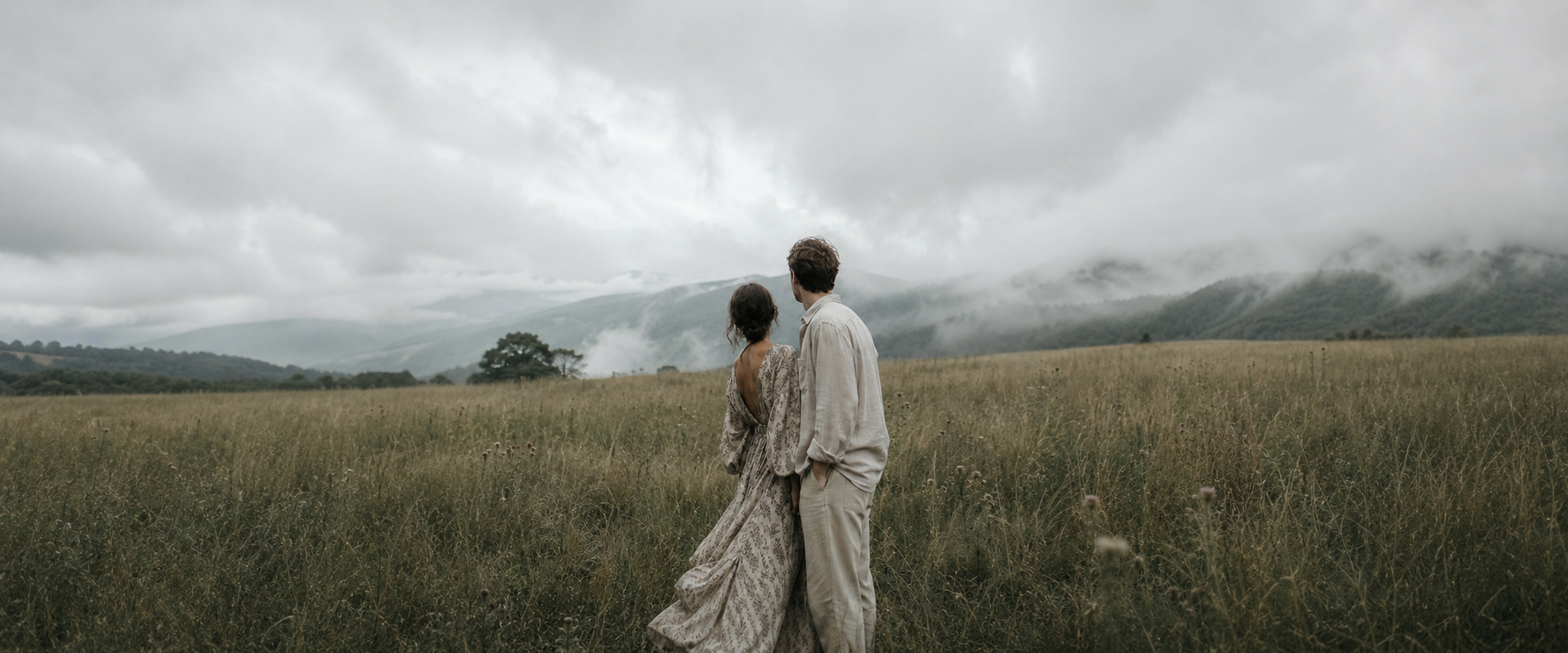 Couple standing in a misty mountain meadow — environmental portrait photography